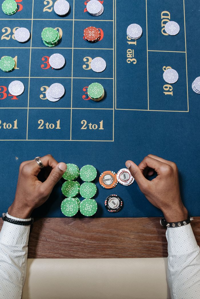 heros-img Hands arranging chips on a roulette table in a casino setting.